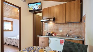 A compact kitchen with wooden cabinets, a built-in stove, and a tiled backsplash. - Caravelle Camping Village (Ceriale)