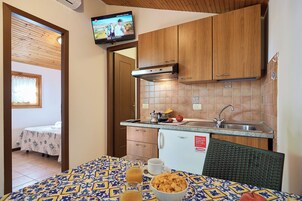 Uma cozinha compacta com armários de madeira, fogão embutido e painel de azulejos.