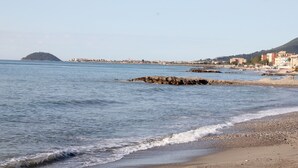 A coastal view with a beach, rocky outcrops, and a distant island. - Caravelle Camping Village (Ceriale)