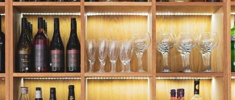 Una licorería bien organizada con estantes repletos de diversas botellas de alcohol, vasos y una exhibición de vasos vacíos.