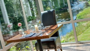 A dining table set with a candle, glassware, and a flower. - Craig-y-Dderwen Riverside Hotel (Betws-Y-Coed)
