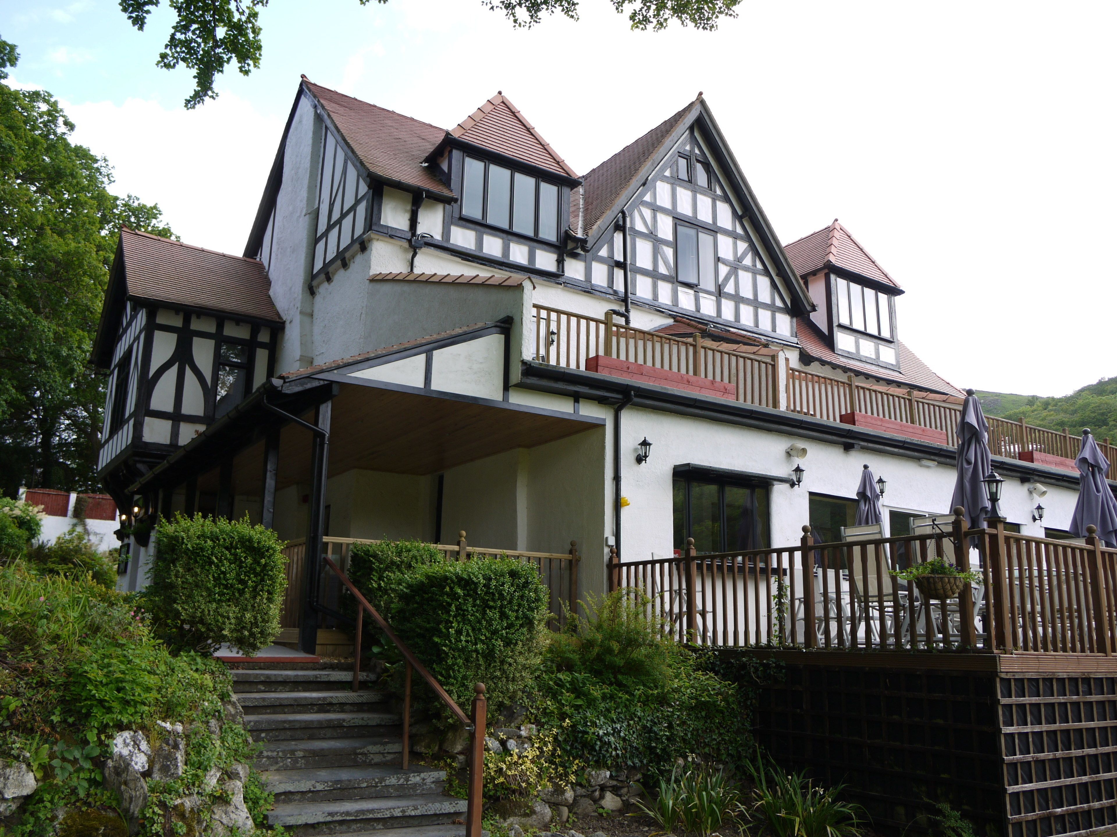 A traditional Tudor-style house with a steeply pitched roof, dormer windows, and a wooden balcony.