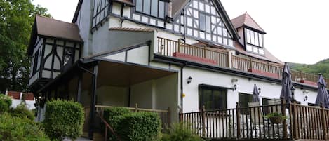 A traditional Tudor-style house with a steeply pitched roof, dormer windows, and a wooden balcony.