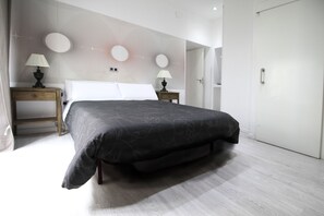 Une chambre moderne avec un grand lit, deux tables de chevet avec des lampes, une armoire et un motif décoratif sur le mur.