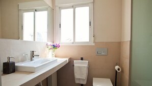 Un baño moderno con lavamanos blanco, inodoro y zona de ducha.