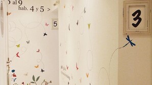 Un pasillo con un mural floral y un cartel con el número 3.