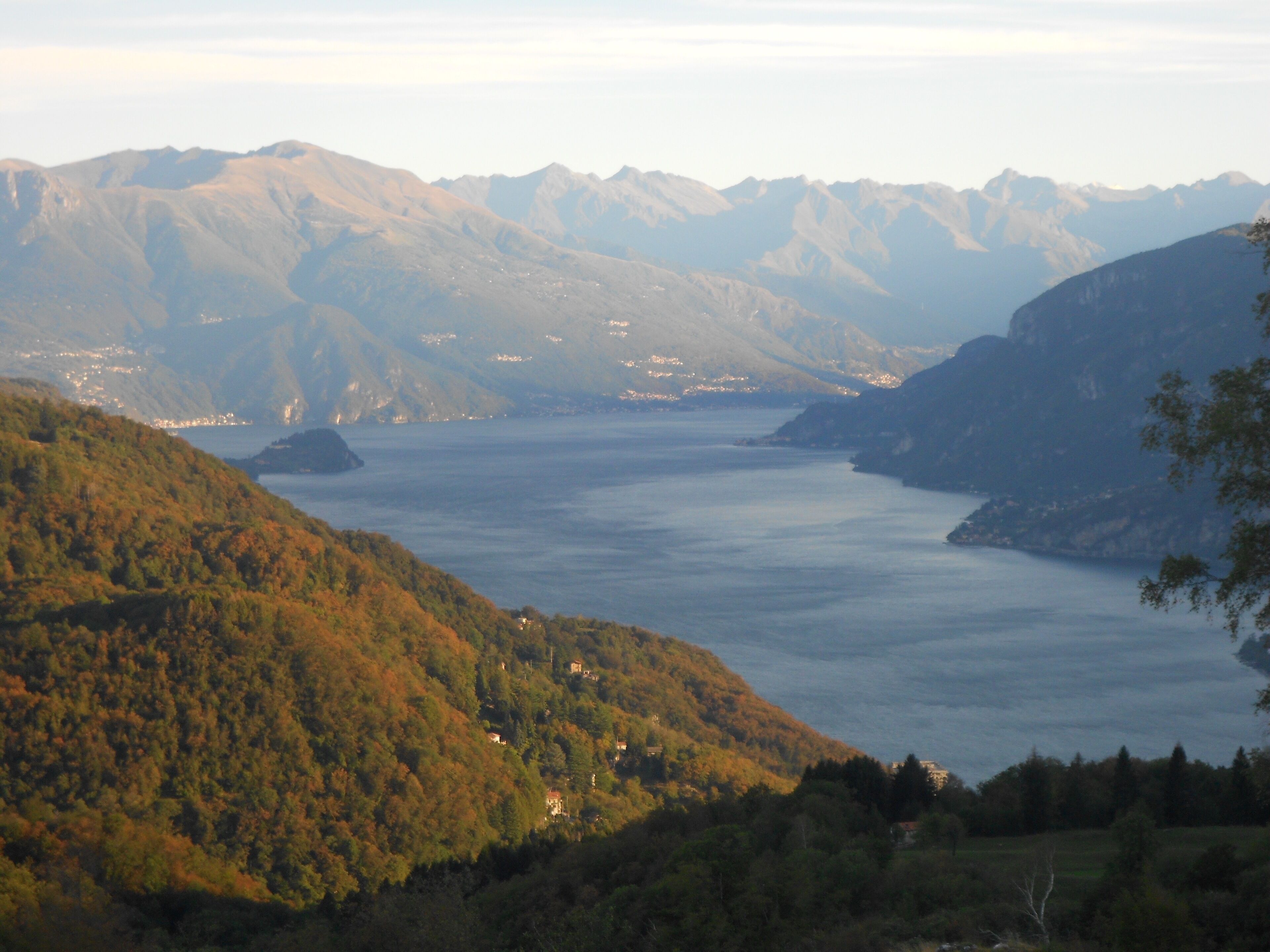 A mountainous landscape with a lake and distant buildings.