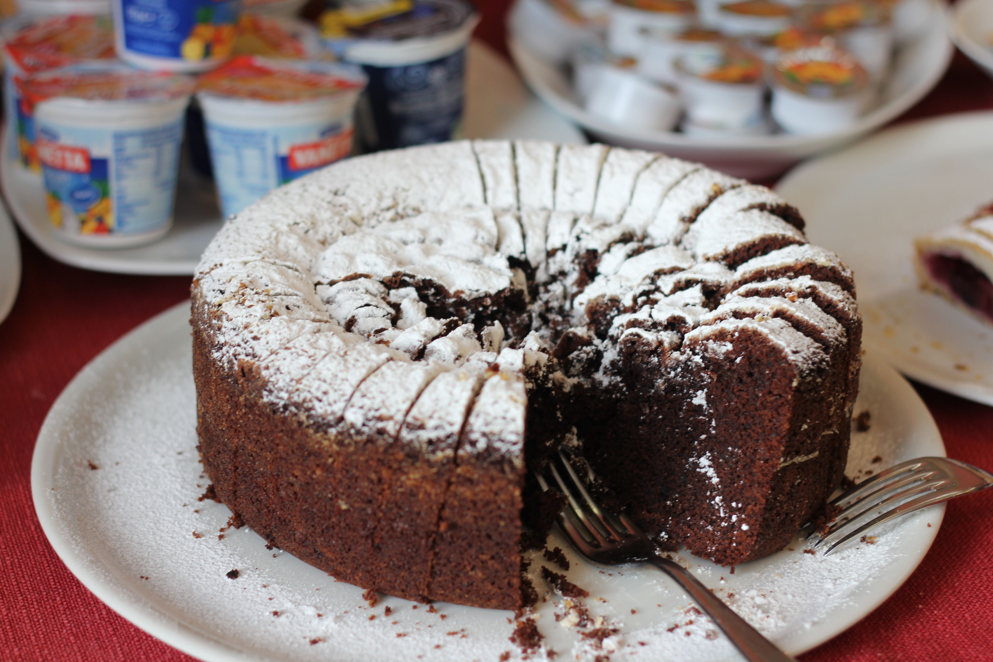 A chocolate bundt cake with a dusting of powdered sugar on a white plate.