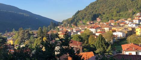 Un village perché sur une colline, avec ses maisons traditionnelles, une végétation luxuriante et un ciel dégagé.
