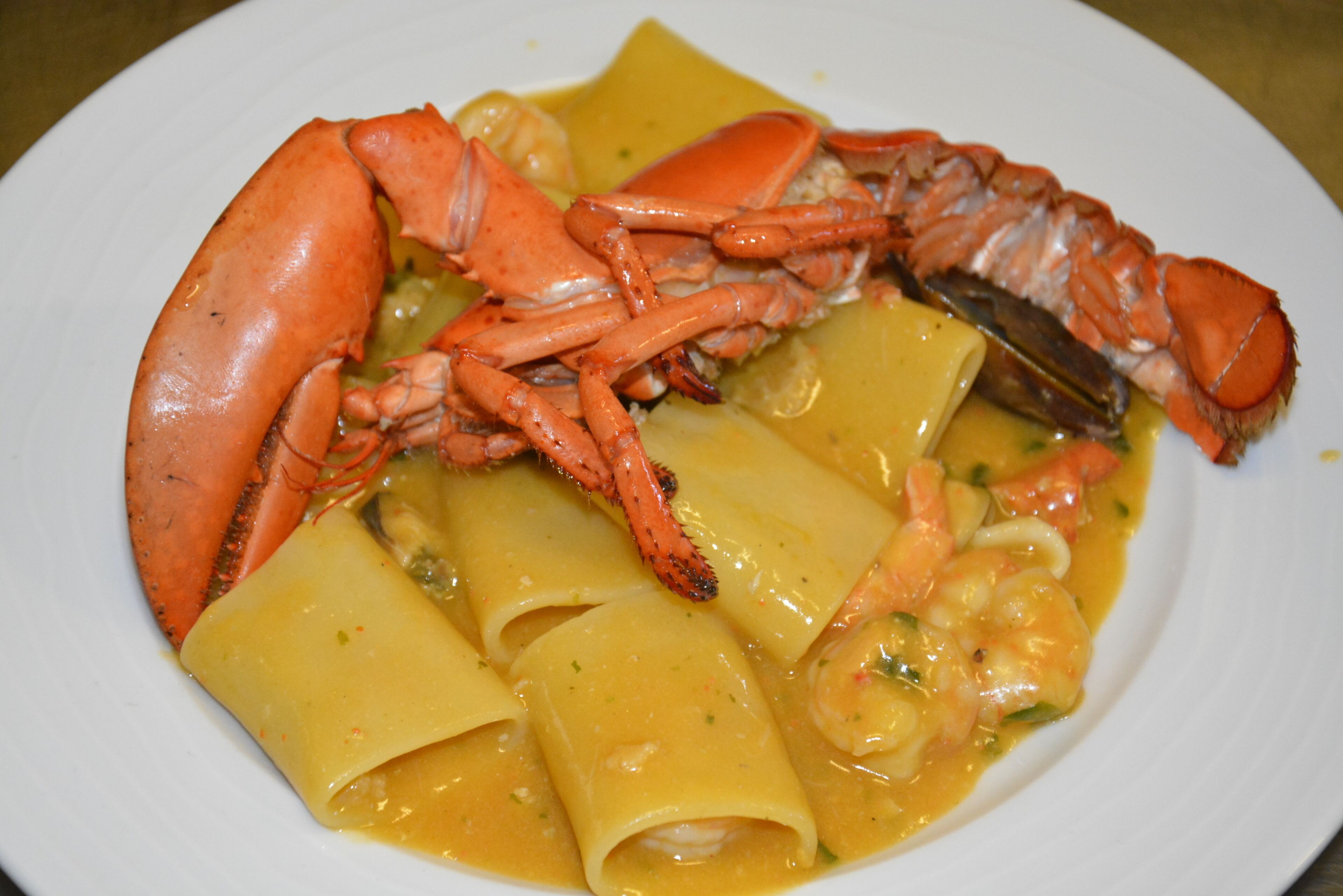 A plate of pasta with shrimp and a lobster tail.