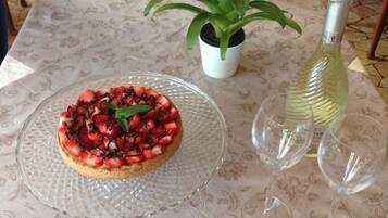 Un postre sobre un plato de vidrio, una planta en maceta y una botella de vino sobre una mesa.