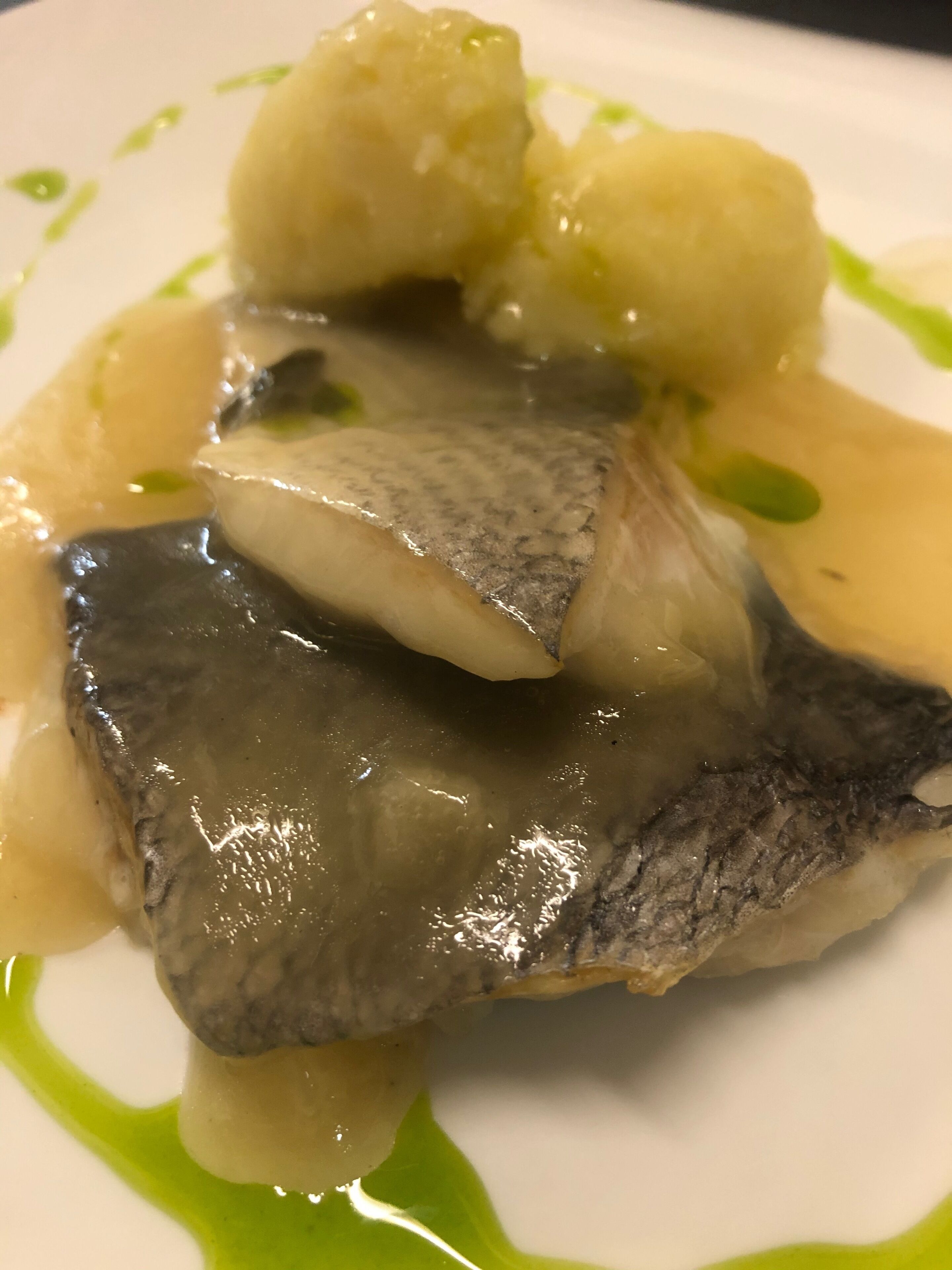 Un plat amb peix, patates i una salsa verda.