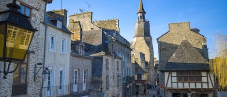 Eine historische Straße mit Steinbauten, einem Kirchturm und einem Café.