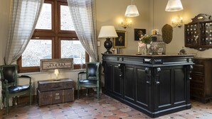 Um quarto com uma janela grande, um armário de madeira, uma cadeira verde, uma mesa pequena com uma luminária e um acessório de iluminação fixado na parede.