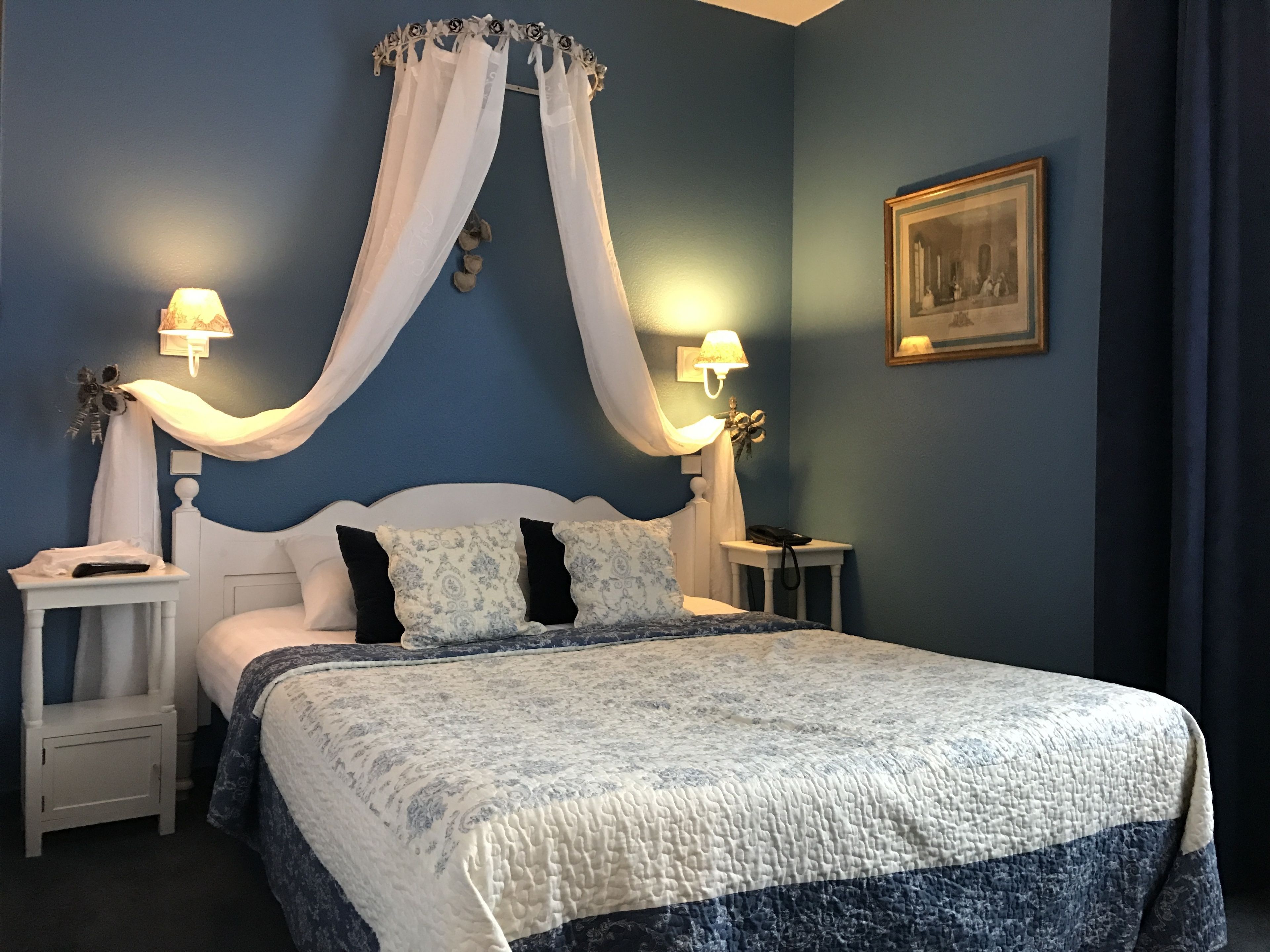 Ein Schlafzimmer mit einem Himmelbett, zwei Nachttischen, einem Beistelltisch und einer Wandlampe.