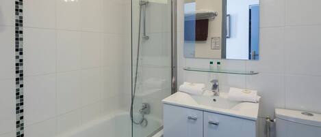 A modern bathroom with a glass-enclosed shower, a white sink with two towel racks, and a toilet.