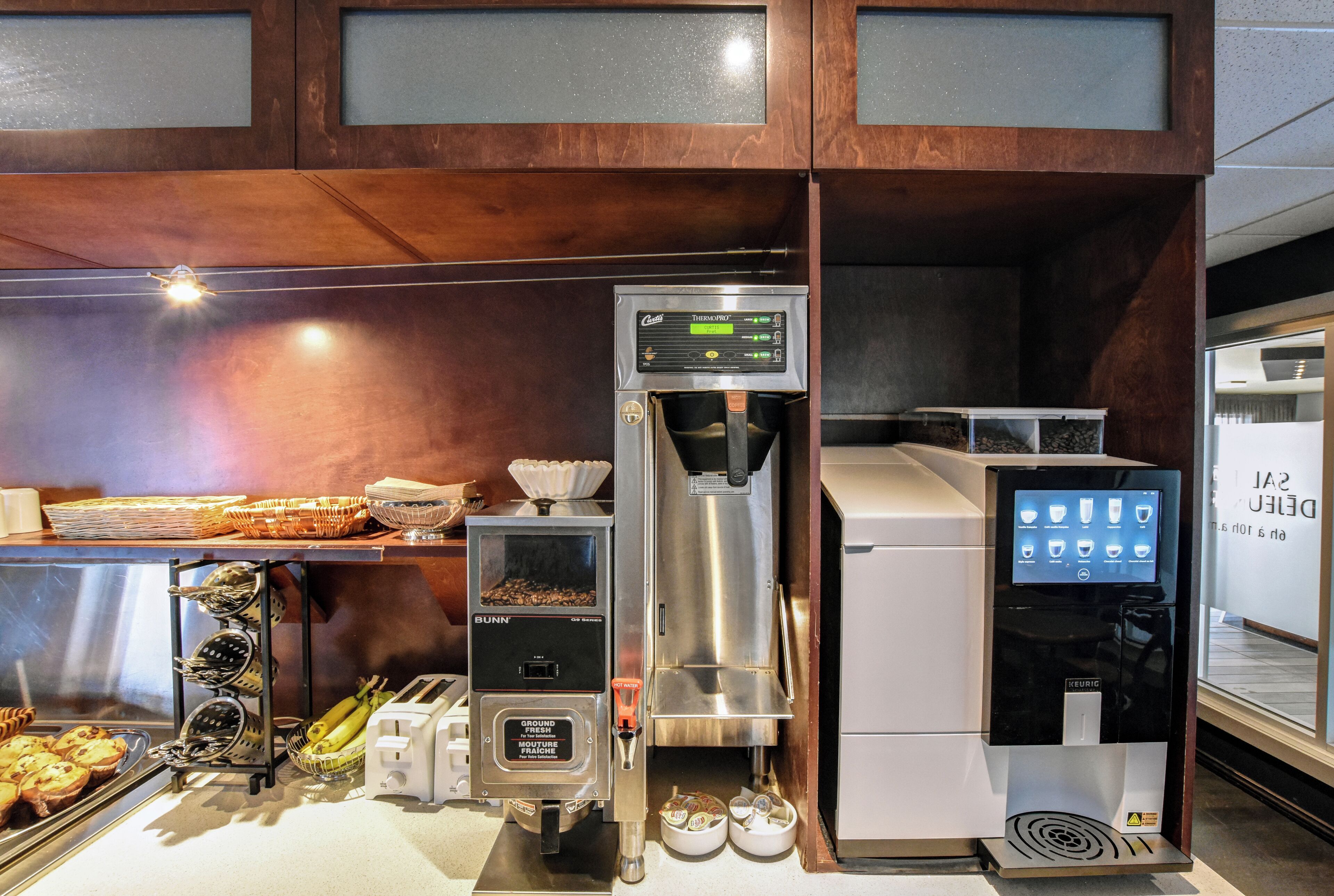 Een koffiehoek met een koffieapparaat, een maler en een waterdispenser.