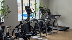 Un gimnasio con cintas de correr, bicicletas estáticas y equipo de ejercicio.