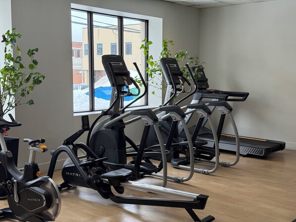 Un gimnasio con cintas de correr, bicicletas estáticas y equipo de ejercicio.