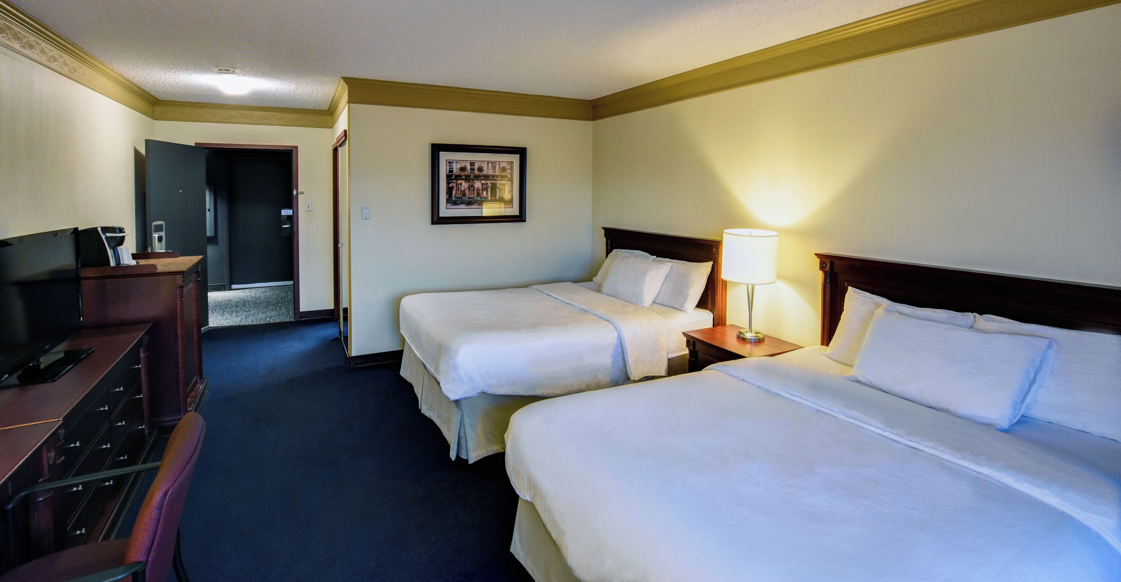 A hotel room with two beds, a desk with a computer, and a television.