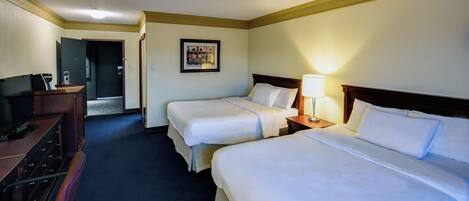 A hotel room with two beds, a desk with a computer, and a television.