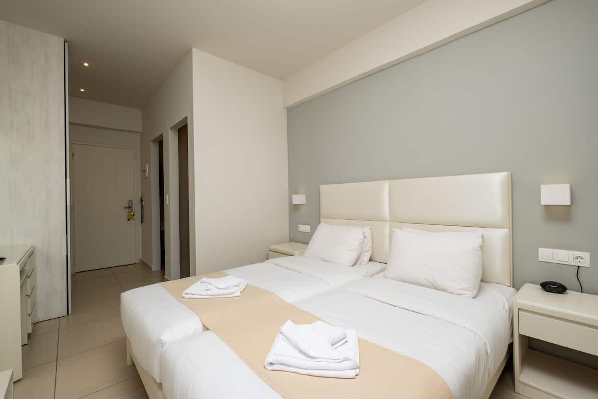Une chambre d’hôtel avec deux lits, un bureau et une chaise.