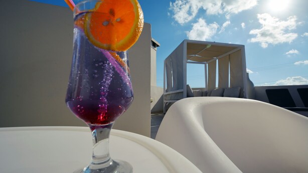 A glass of red drink with an orange slice on a white table. - Dimitrios Beach Hotel Adults Friendly 14 plus (Rethymno)