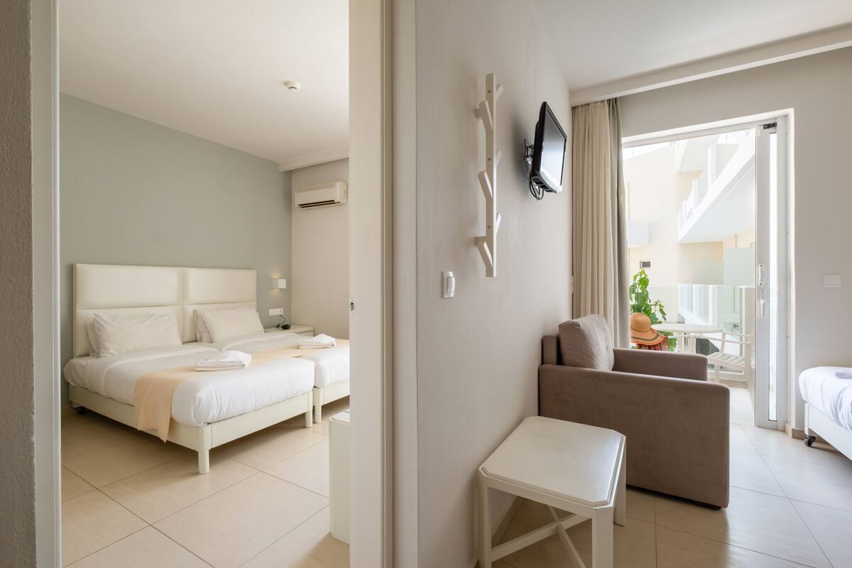 Une chambre d’hôtel moderne, dotée d’un grand lit, d’un canapé, d’une petite table et d’un téléviseur fixé au mur.