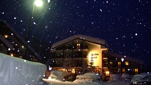 Un hotel con fachada nevada, ventanas iluminadas y una señal visible.