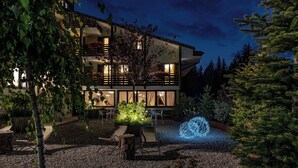 Un edificio de varios pisos con balcón, mobiliario exterior y una instalación de luces decorativas.