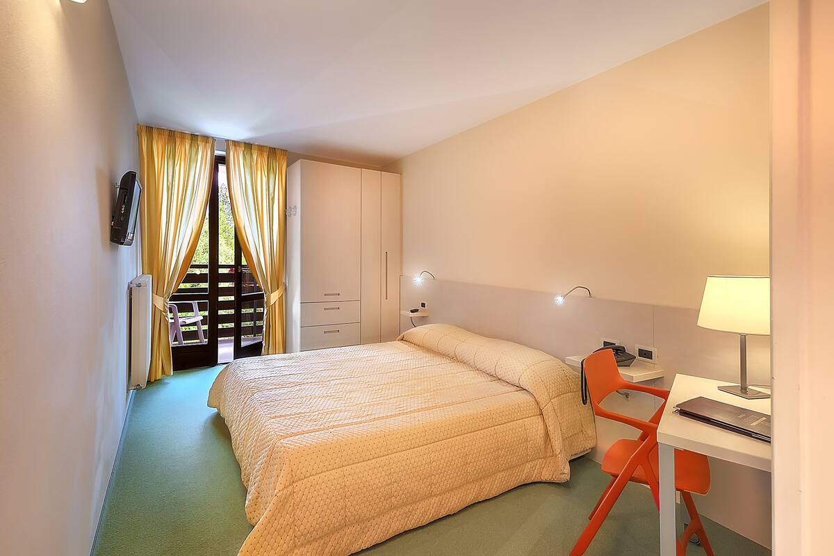 A bedroom with a bed, a desk, a chair, and a wardrobe.