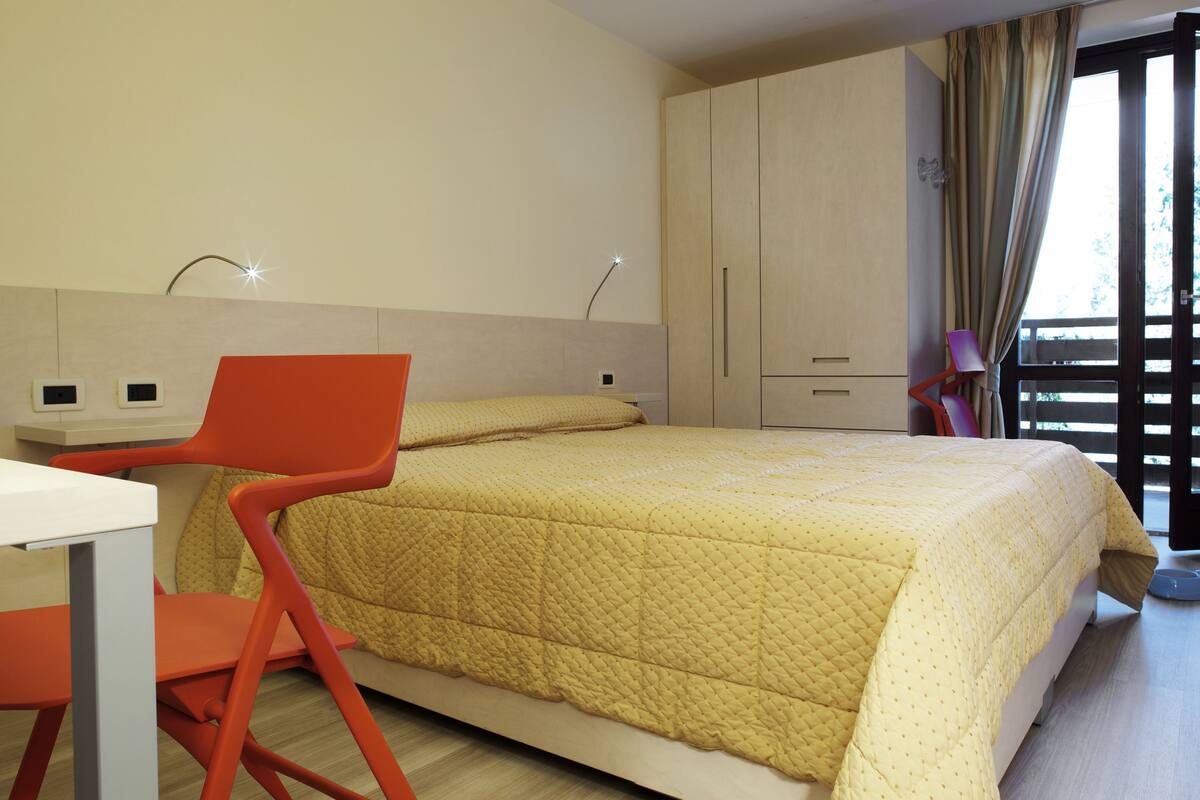 A bedroom with a bed, a desk, and a chair.