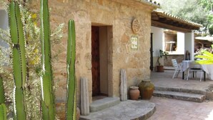 A rustic stone building with a door and steps leading to a patio area. - Hostal Residència Catalina Vera (Andraitx)