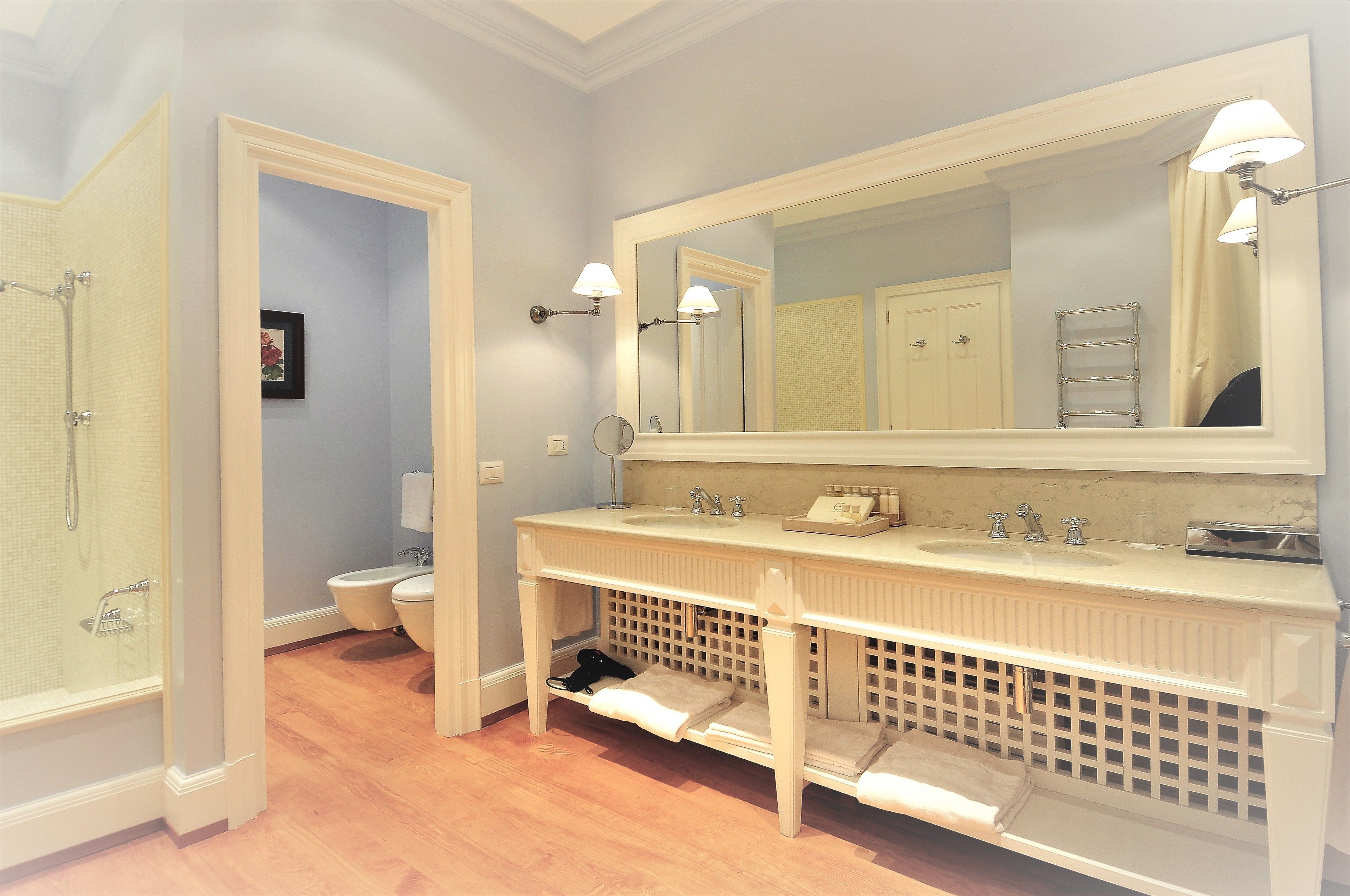 A bathroom with a double sink, a large mirror, and a shower.