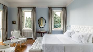 A bedroom with a large bed, a chair, a table, and a mirror.