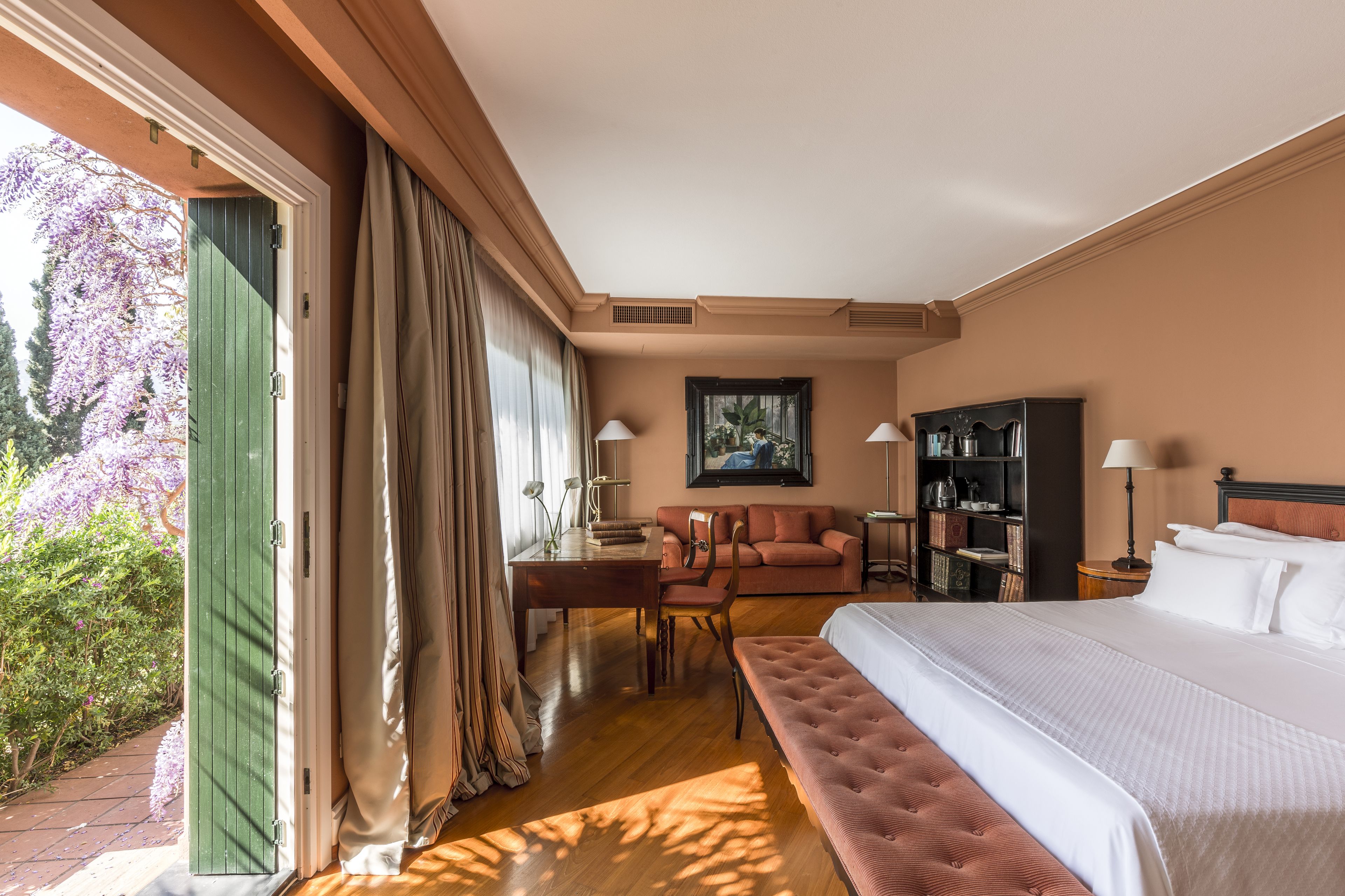 A hotel room with a bed, a sofa, a desk, and a bookshelf.