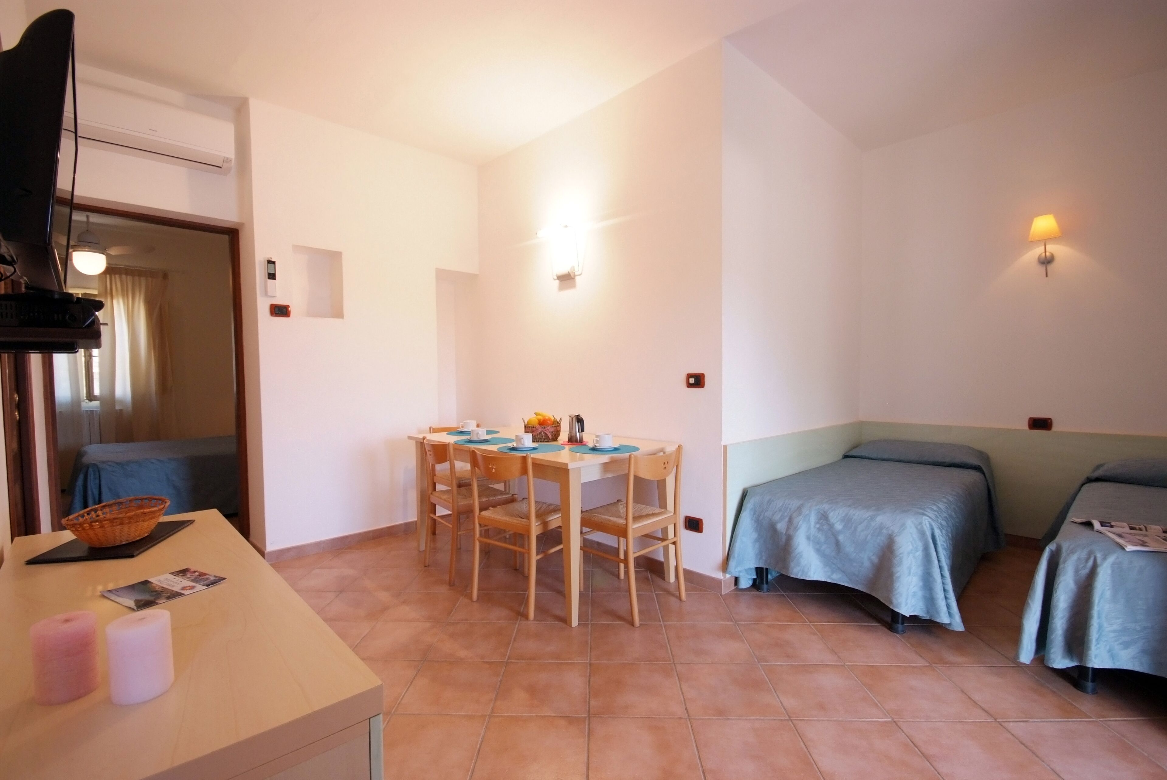 A room with a dining table, chairs, a bed, and a TV.