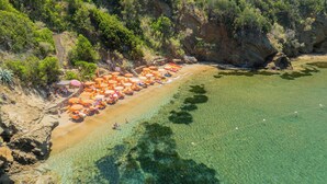 Ein Strand mit klarem Wasser, Sonnenschirmen und Liegestühlen.