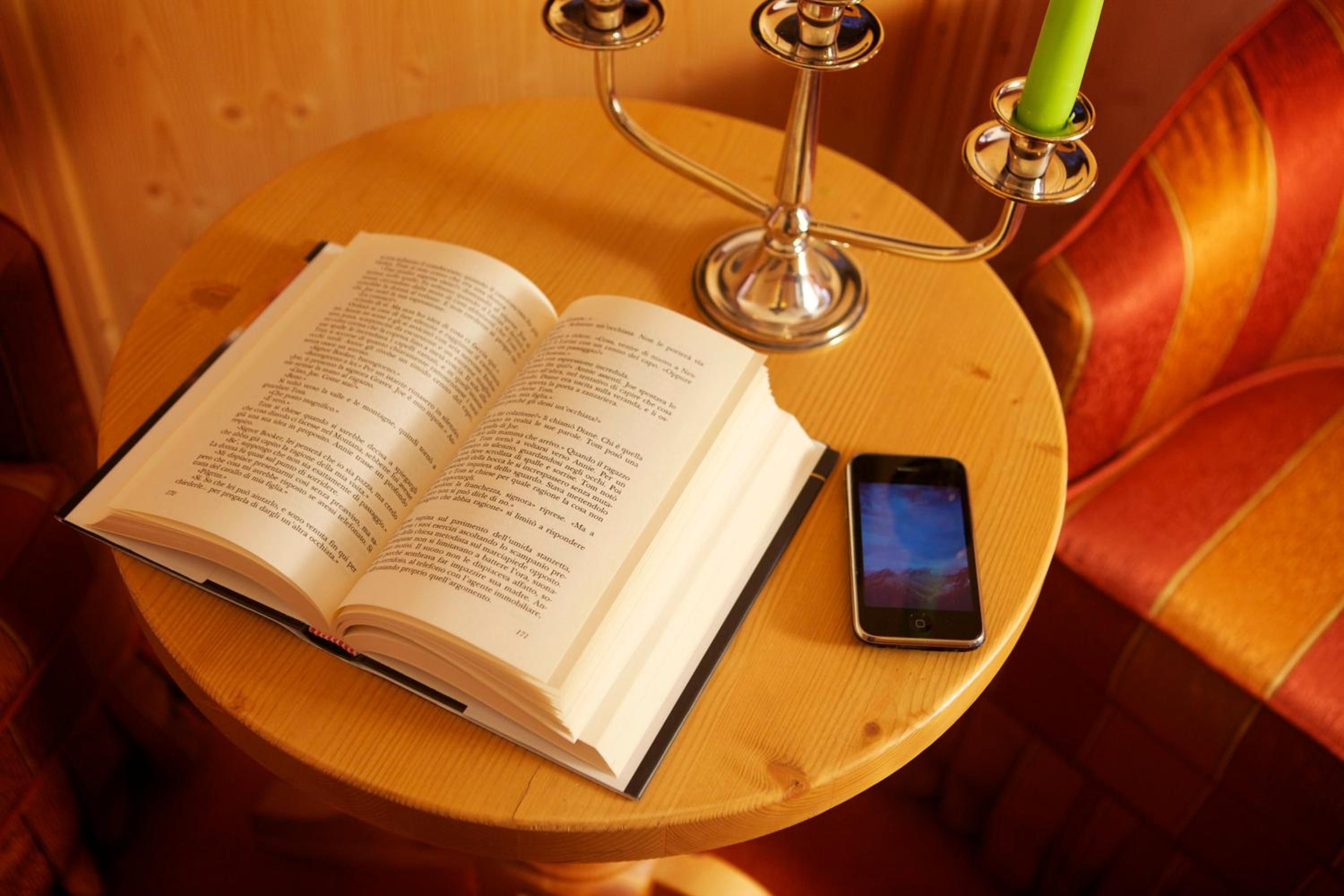 Un libro aperto su un tavolo di legno, con uno smartphone accanto.