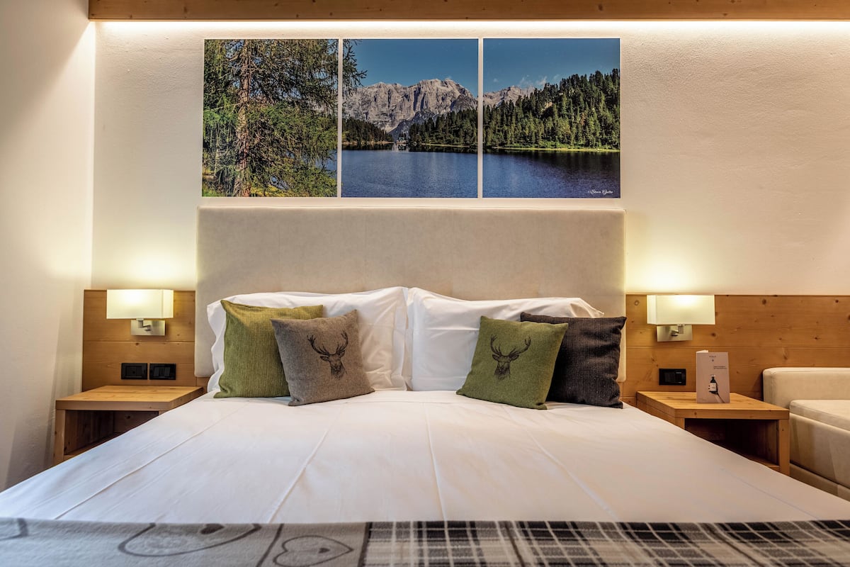 A hotel room with a large bed, two nightstands with lamps, and three framed pictures on the wall.