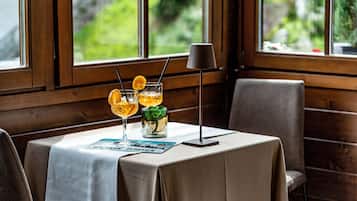 Un tavolo con un menu, due bevande con fettine d'arancia e una lampada.