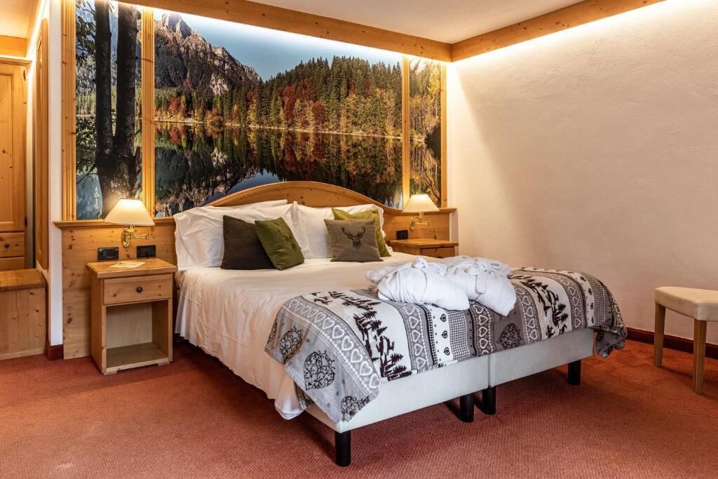 Una cama con un edredón estampado, dos mesitas de noche y una mesita auxiliar.