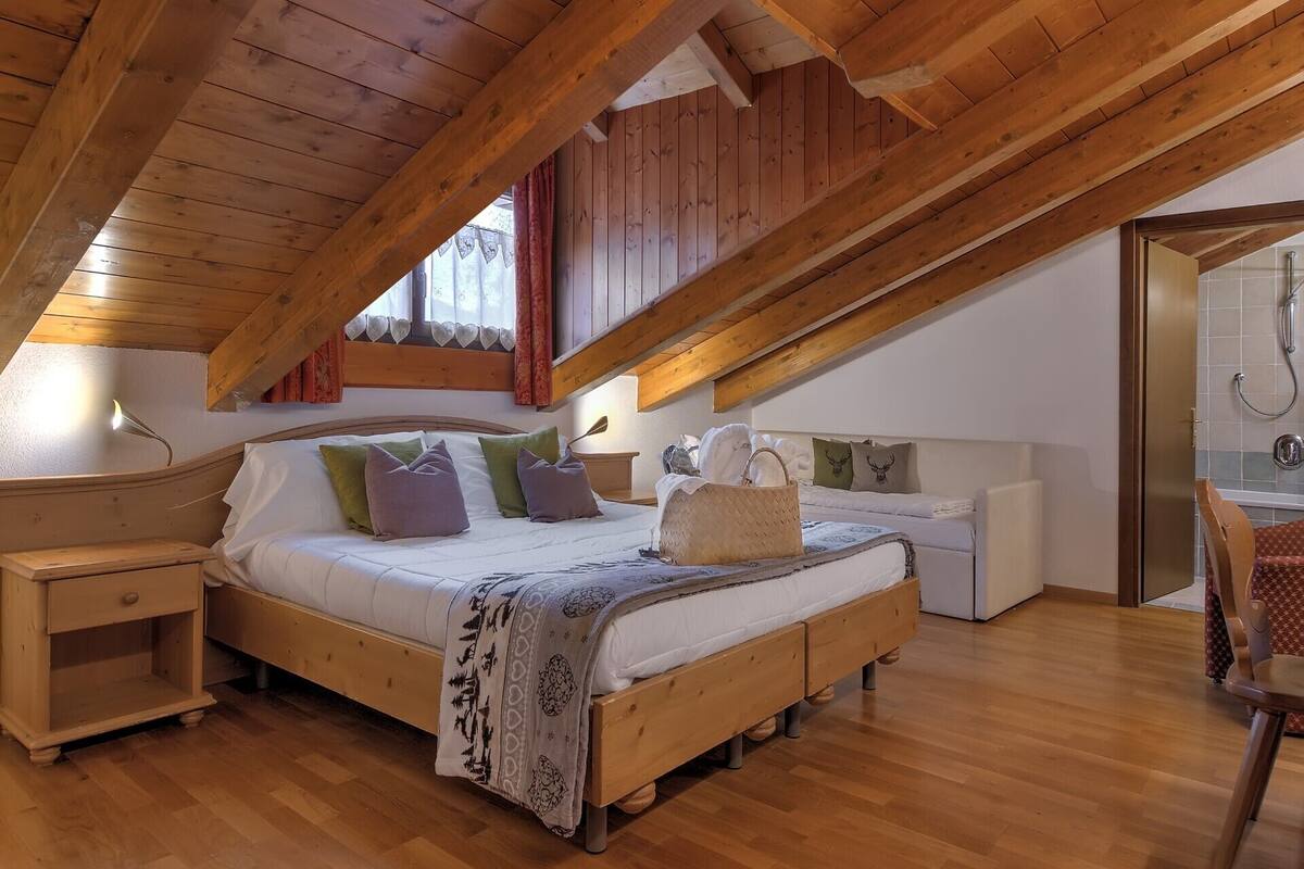 A bedroom with a wooden ceiling, a bed with multiple pillows, a bedside table, and a nightstand.