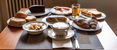 Una mesa servida con diversos productos para el desayuno, como pasteles, pan y una taza de té.