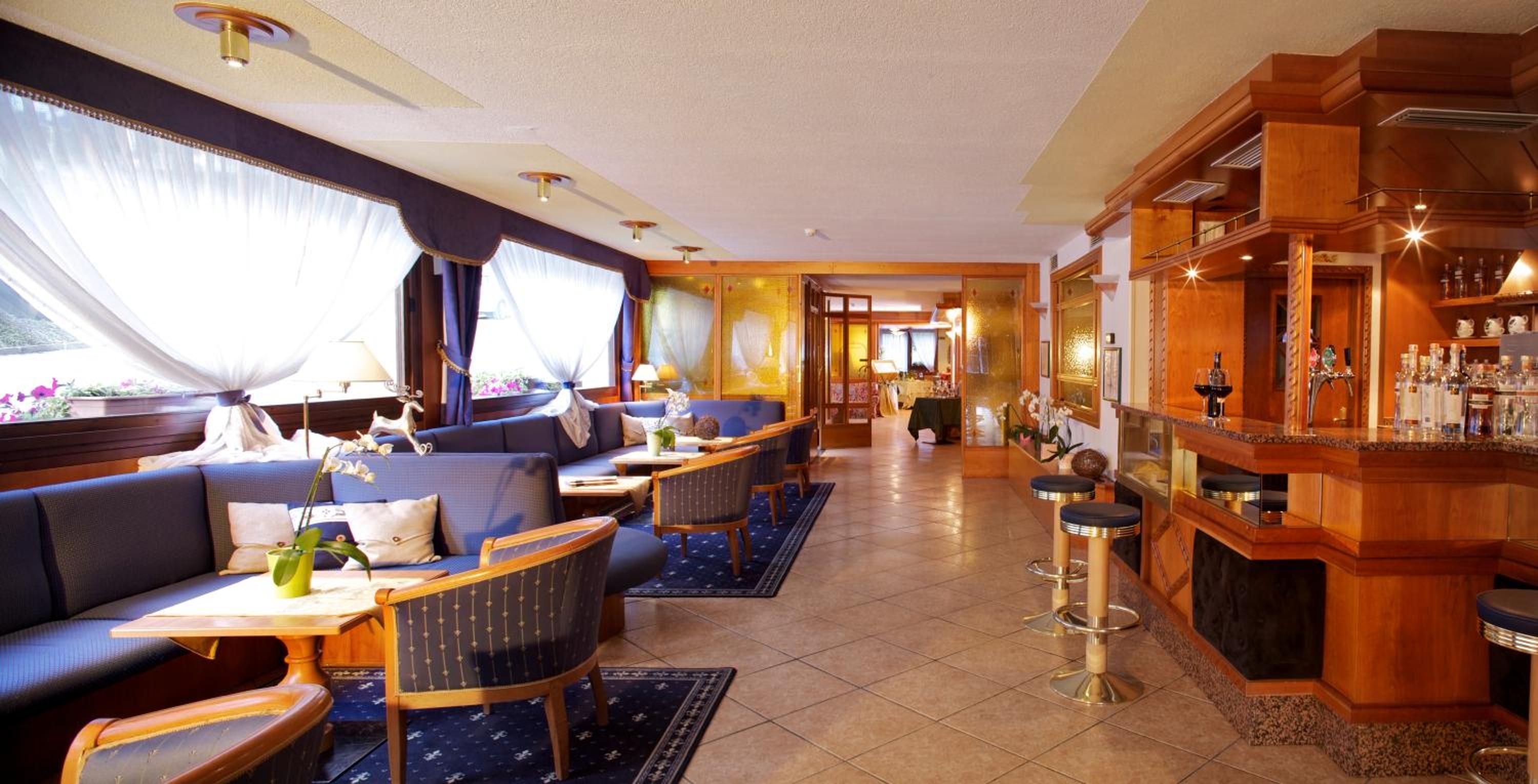 Un hall d’hôtel doté d’espaces aménagés avec des sièges, d’un bar et offrant une vue sur l’extérieur.