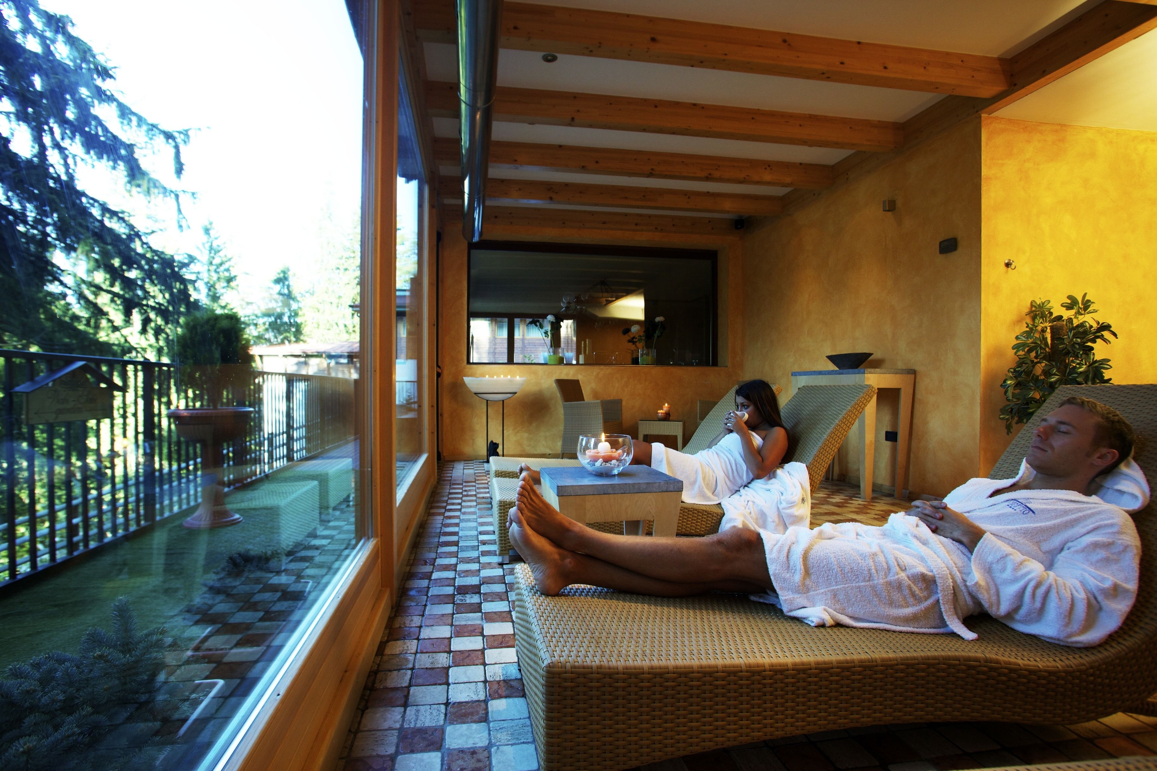A room with wicker furniture, a tiled floor, and a view of the outdoors.