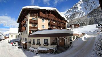 A multi-story chalet with a snow-covered roof and a ski lift in the background.