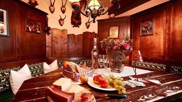 A wooden dining table with a variety of food items, including cheese, meats, fruits, and bread.