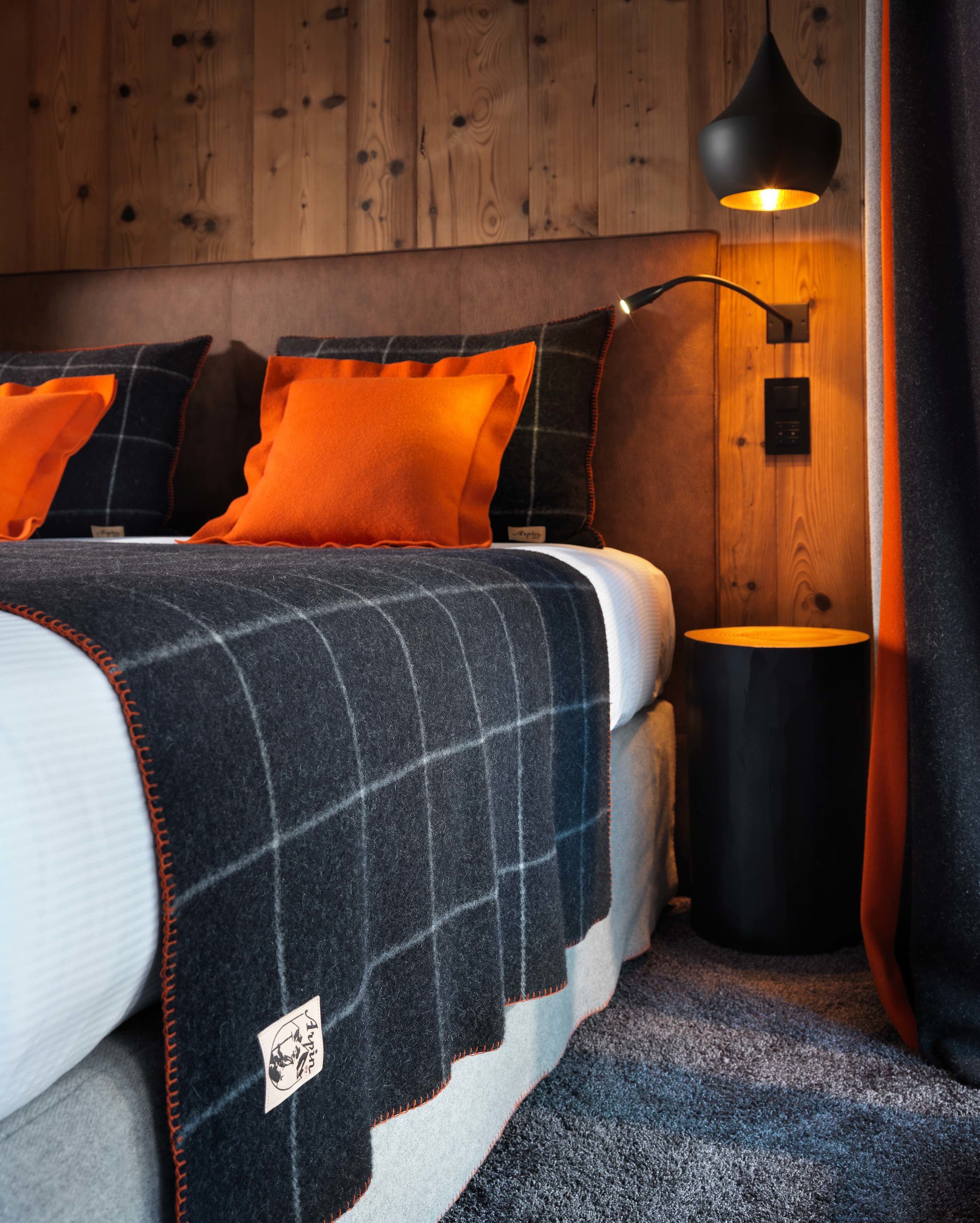 A bedroom with a bed, a bedside lamp, and a wooden wall.