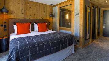 A bedroom with a large bed, wooden walls, a window with blinds, and a door.